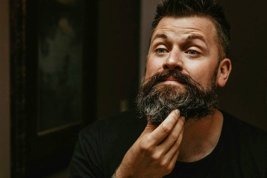 Outdoorsman looking in mirror and grooming beard